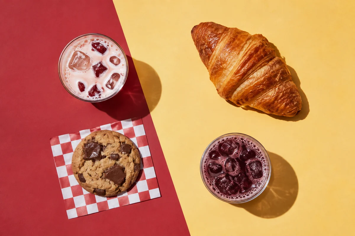 Cherry and berry sodas, a croissant, and a chocolate cookie on colorful paper